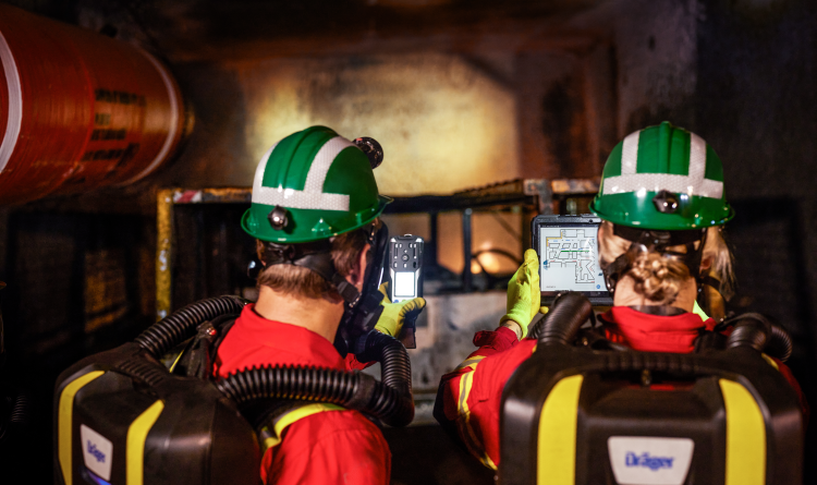 A group of miners wearing headlamps are standing in an underground passage.