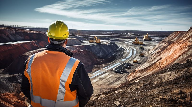 Panoramic view of a construction worker stood on the outskirts of a mine field looking down into it with a hard hat and high visible vest to support abandoned mines article