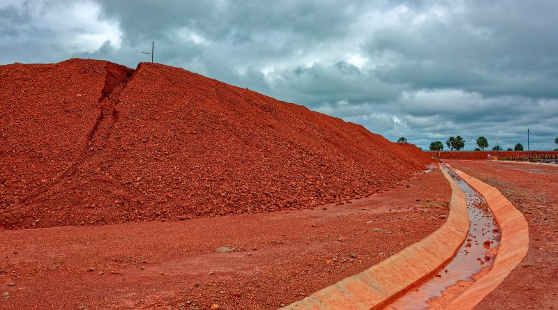 Large piles of bauxite ore, which is refined into aluminum, sit at a treatment area storage of bauxite. Guinea, Africa.