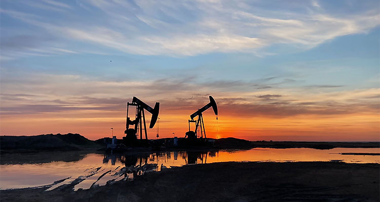 two oil drilling rigs at dusk