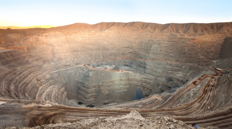A wide view of an open pit mine showing terraced layers and heavy machinery