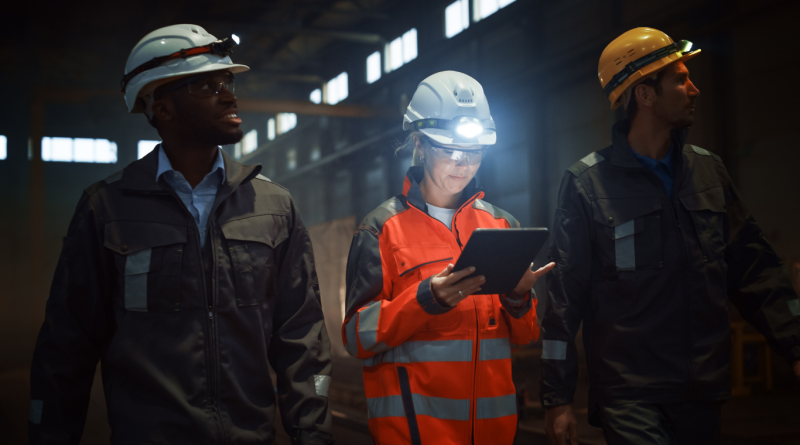 Mining engineers in safety gear inspecting data inside an industrial facility.