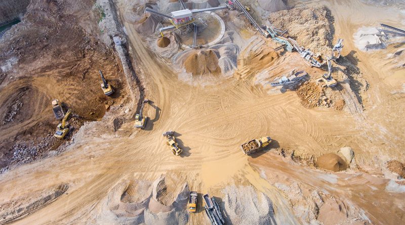 Open-pit gold mine in Ontario with excavators and haul trucks at sunset, representing Barrick's sale of Hemlo mine